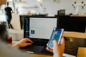 Haker przy laptopie analizujący profil ofiary, ukierunkowany atak spear phishing