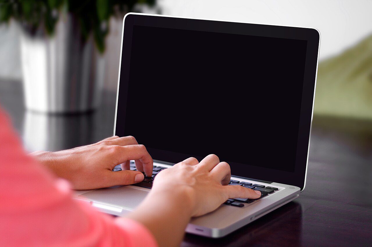 Dłonie piszące na klawiaturze laptopa