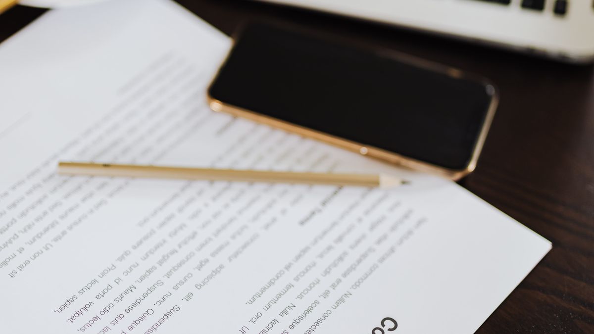 Smartfon leżący na wydrukowanym dokumencie obok długopisu