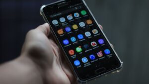 Ekran telefonu z Androidem pełen ikon aplikacji trzymany w dłoni