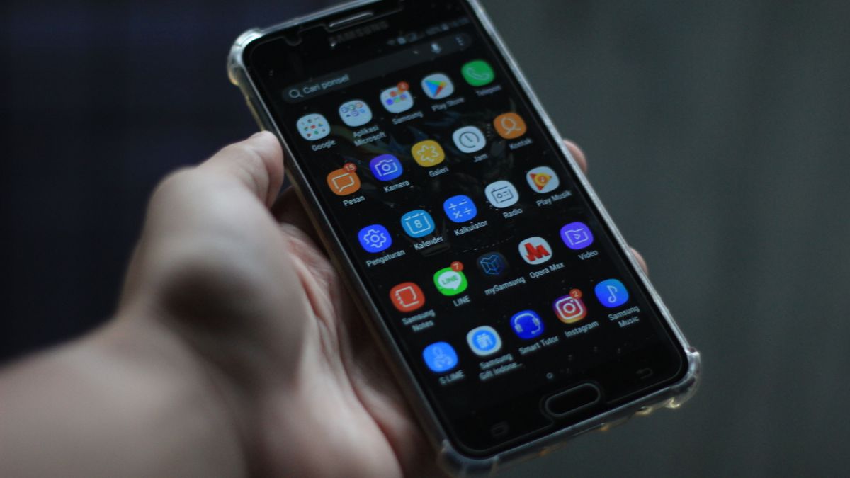 Ekran telefonu z Androidem pełen ikon aplikacji trzymany w dłoni