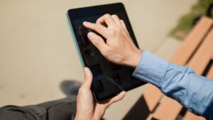 Osoba korzystajaca z tabletu na lawce w sloneczny dzien