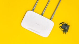 Domowy router Wi-Fi z antenami i zasilaczem na zoltym tle