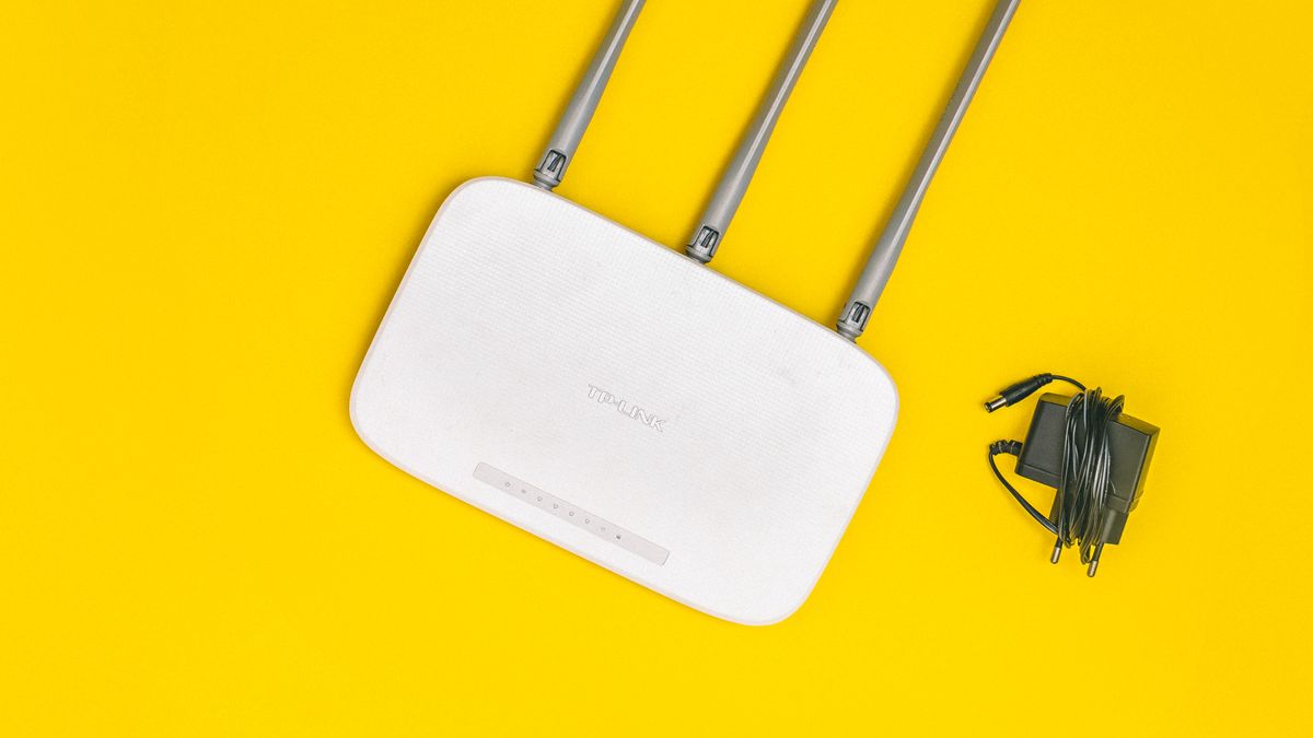 Domowy router Wi-Fi z antenami i zasilaczem na zoltym tle