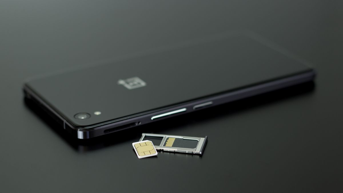 Karta SIM na wysuniętej tacce obok smartfona