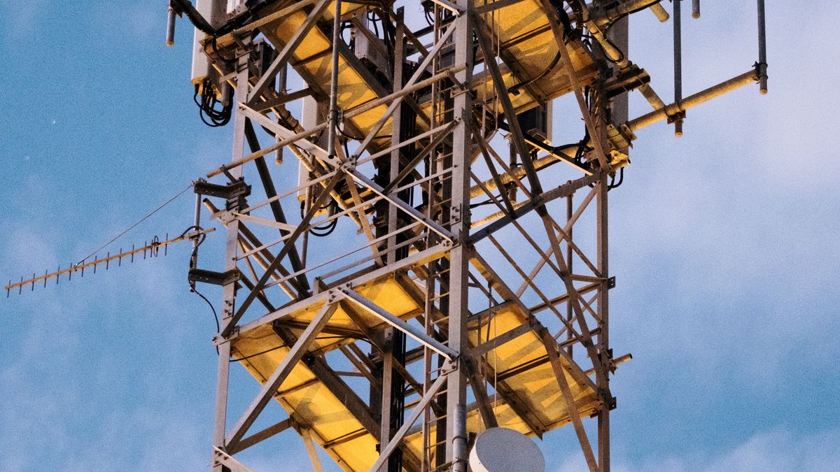 Maszt telekomunikacyjny z antenami sektorowymi na tle nieba