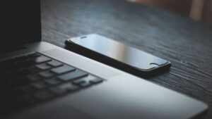 Smartfon leżący obok otwartego laptopa na biurku