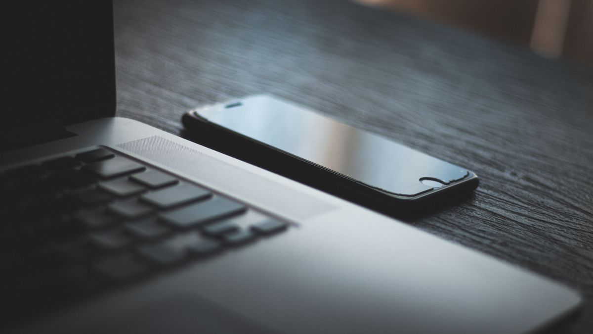Smartfon leżący obok otwartego laptopa na biurku