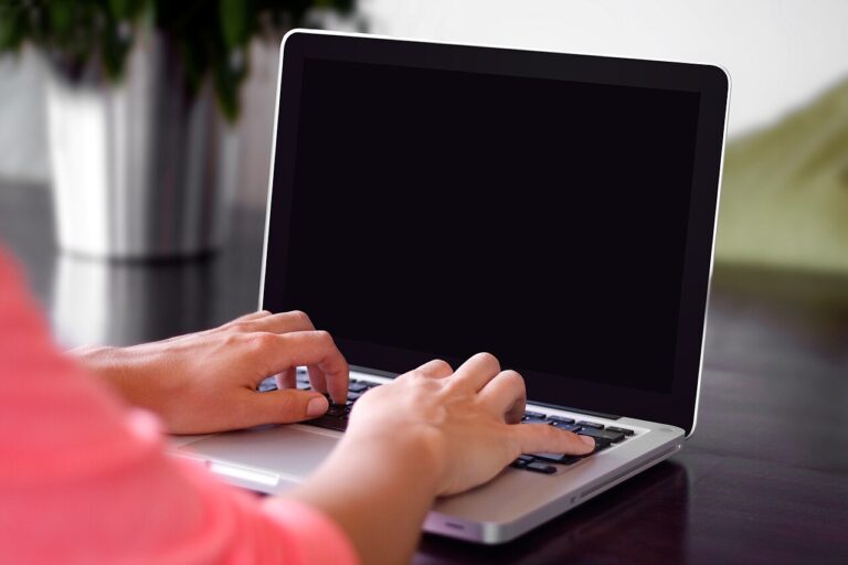 Dłonie piszące na klawiaturze laptopa