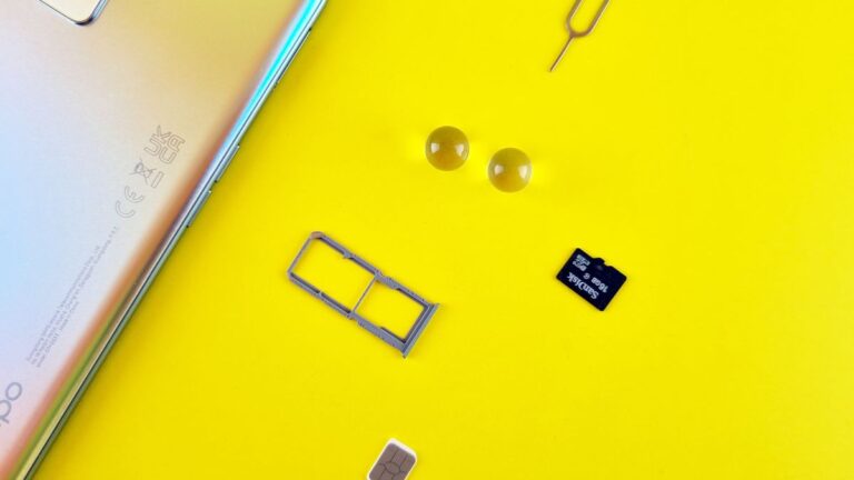 Tacka na kartę SIM, karta microSD i szpilka obok smartfona