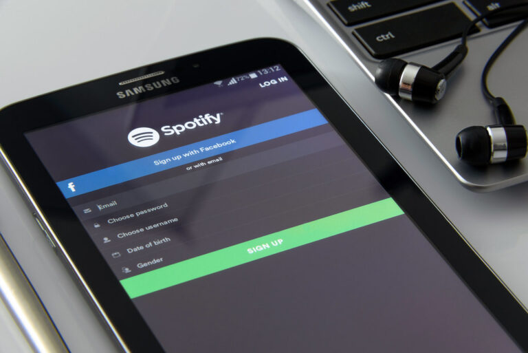 Aplikacja Spotify na smartfonie obok słuchawek dousznych
