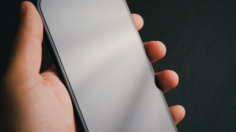 Dłoń trzymająca smartfon z pustym, wygaszonym ekranem