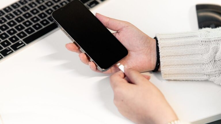 Podłączanie kabla do smartfona obok klawiatury laptopa
