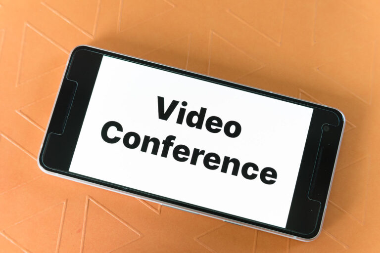 Smartfon z napisem Video Conference na pomarańczowym tle