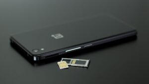 Karta SIM na wysuniętej tacce obok smartfona