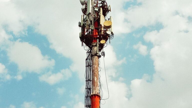Maszt telekomunikacyjny z antenami sektorowymi na tle nieba