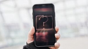 Telefon w dloni z znakiem zapytania na ekranie, nieznane polaczenie